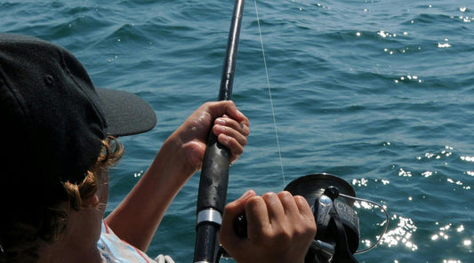 Close-up of a person holding a fishing rod over water emphasizing fishing health benefits