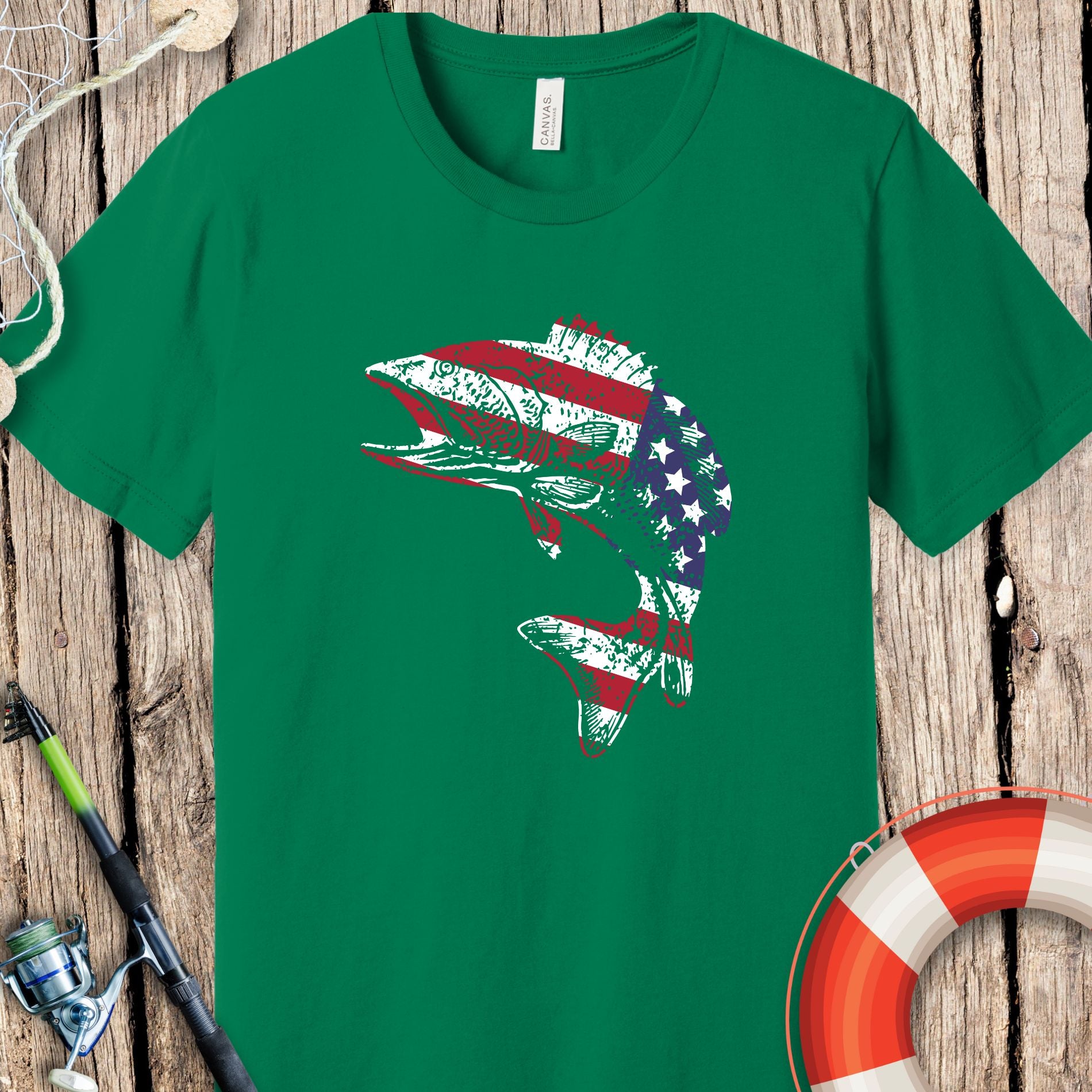 Green Printify fishing t-shirts with American flag fish design on wooden background